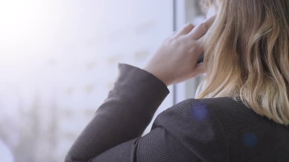 Female Office Worker Talking Over Phone Near Window, Important Business Call