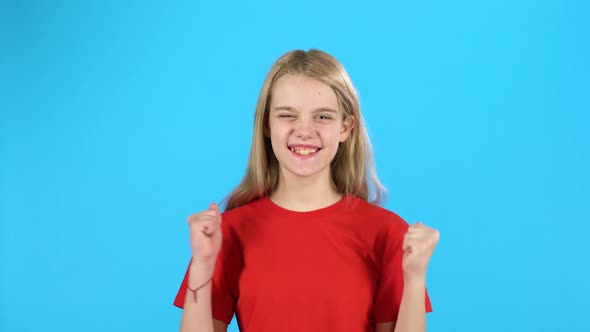 Little Blonde Is Happy with the Victory, She Dances with Happiness on Blue Background