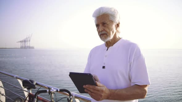 Portrait of Retirement Handsome Senior Man Using Tablet Computer on Seafront Slow Motion