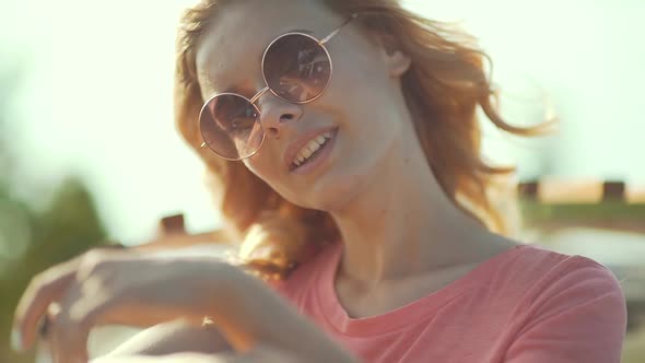 Beautiful Girl In Sunglasses Enjoying Summer Sun. Happy Smiling Woman Having Fun On Wind 