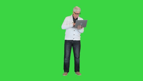 Old Man Standing and Using a Laptop Computer on a Green Screen Chroma Key