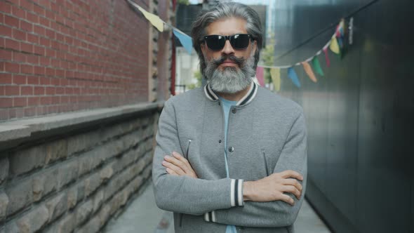 Slow Motion Portrait of Confident Mature Man Standing Outside with Arms Crossed Wearing Sunglasses