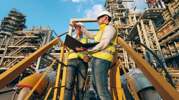 Petroleum Refinery Plant with Two Workers Discussing a Project