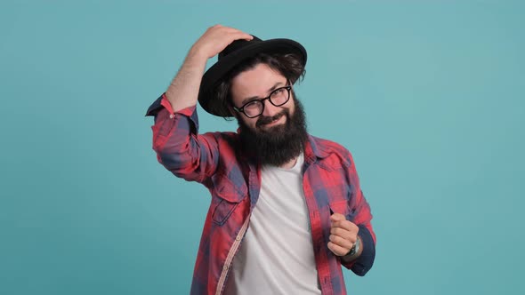 Bearded Man in Casual Outfit and Glasses. He Smiling, and Taking a Hat Off.