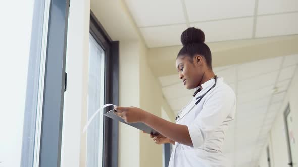 Female African American Doctor or Intern Examines Xray of Lungs Holding It in Hands Indoors