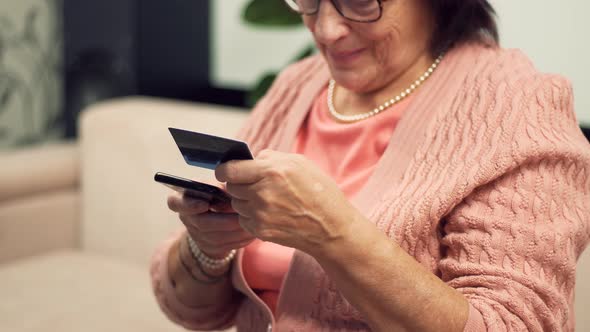 Senior Woman Using Mobile Phone Credit Card Shopping Online At Home. Mature Woman Online Banking.