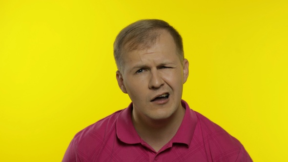 Portrait of Young Caucasian Man Posing in Pink T-shirt. Dissatisfied, Picky Guy Looking To Camera