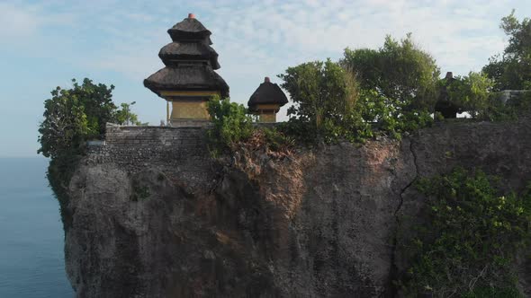 Aerial Flying Low Rising Up Vertically past cliff showing a temple and landscape in Bali