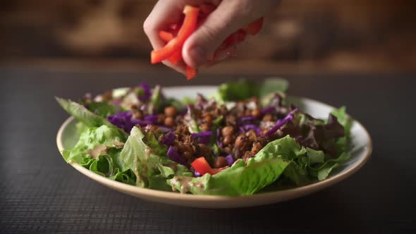 Chefs Hand Serving Salad with Sliced Red Bell Pepper