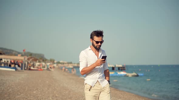 Freelancer Remote Working At Seacoast Beach Using Mobile Phone Call To Colleagues. Smartphone.