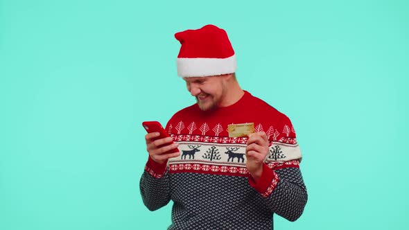 Man in Christmas Red Sweater Use Mobile Cell Phone and Plastic Credit Bank Card Win Calebrate Wow