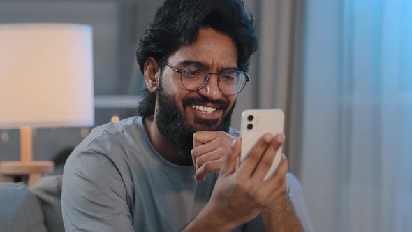 Arabic Bearded 30s Man in Glasses at Home with Mobile Phone Talking on Video Call Conference Chat