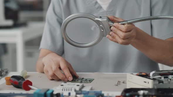 Female Technician Examining PCB with Desk Magnifier