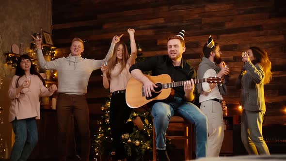 Group of Young Friends Are Dancing and Singing at the Christmas Party.