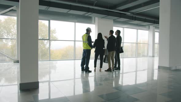Diverse Group of Businesspeople Standing Inside Newly Constructed Industrial Building Talking