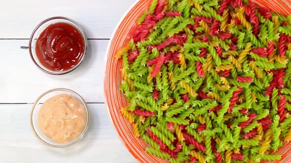 Multicolored Uncooked Raw Italian Fusilli Pasta Rotating Slowly on Turntable in Dish