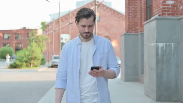 Man Feeling Angry While Using Phone Outside