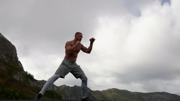 Alone Fighter is Training in Mountain Sportsman is Practicing Punches Outdoors