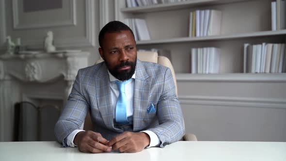 A Serious African-American Man with a Beard and a Stylish Gray Suit. The Businessman Is in a Bright