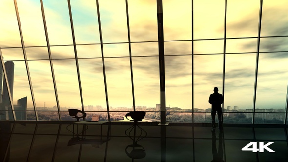 Businessman in front of a panoramic office window 4K alt