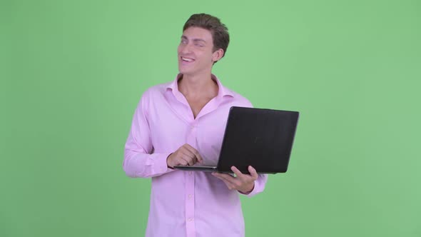 Happy Young Handsome Businessman Thinking While Using Laptop