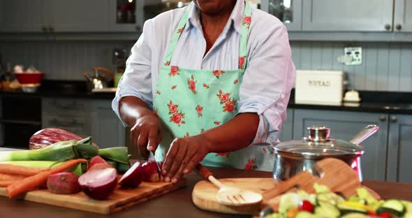 Senior woman chopping vegetables in kitchen