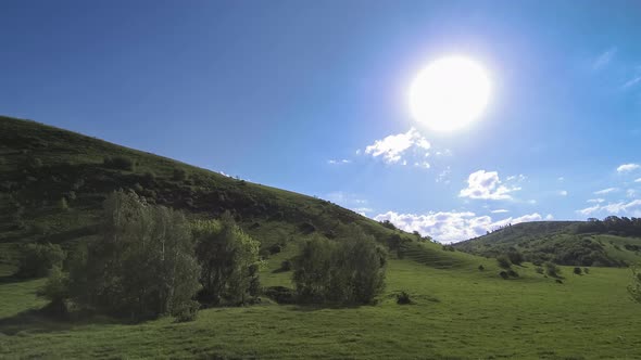  UHD Mountain Meadow Timelapse at the Summer. Clouds, Trees, Green Grass and Sun Rays Movement.