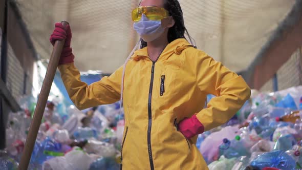 Portrait of a Girl with Dreadlocks in Yellow Jacket and Mask Holding Large Duck Shovel Standing at a