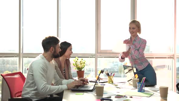 Cheerful Lady Showing Paper To Colleagues in Office.