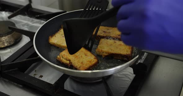 Close up of slice of potato pancake frying in butter or oil in professional restaurant kitchen from