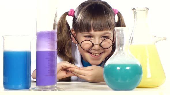 Cute Little Girl with Two Ponytails in Uniform, Round Glasses Stands Up and Smiling Among Chemical