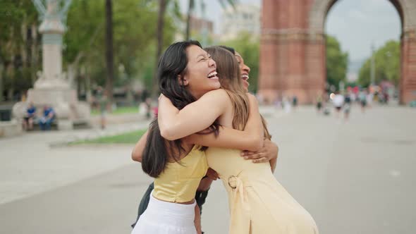 Three Overjoyed Multiracial Female Friends Embracing and Feeling Excited to Meet Outdoors
