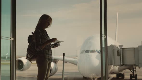 A Silhouette of a Woman with Boarding Documents in Hand, Awaiting Landing on Her Flight