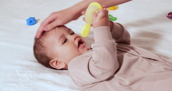 Mother Combing Tiny Hairs on Her Newborn Baby's Head As She Wakes Up