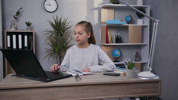 Teen Girl Working Under Her Hometask Using Computer and Private Notepad