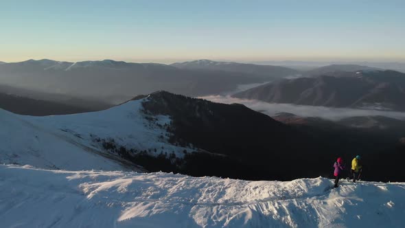 Drone Passing Couple of Hikers, Walking on Mountain Ridge in Winter