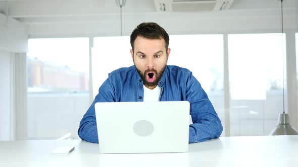 Beard Man In Shock While Working on Laptop in Office Wondering