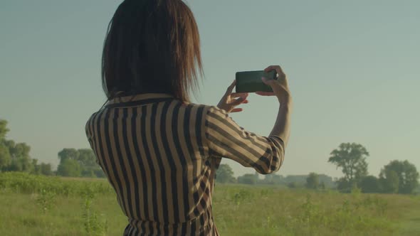 Rear View of Cheerful Woman Photographing Scenic Summer Nature on Cellphone