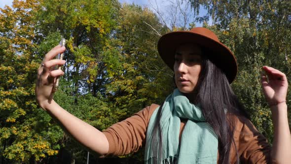 Middle Eastern Woman Taking Selfie in the Park. Mid-autumn, Beautiful Landscape of the Park in the