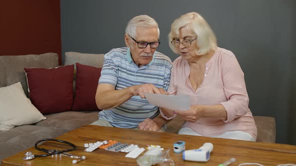 Senior Couple Looking at Medicine Prescription, Pills, Tablets at Home. Coronavirus Lockdown