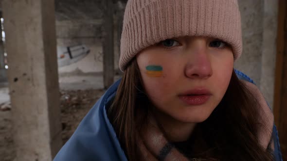 Portrait of a girl refugee with a Ukrainian flag on her cheek against in bomb shelter. War in Ukrain