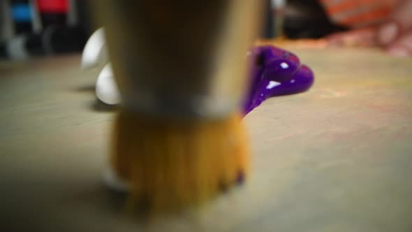 Closeup Shot of Artist Holding Paint Brush and Mix Color on Wooden Palette