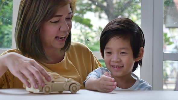 Asian Mother And Son Playing Wood Toy Car Together