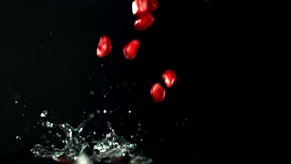 Super Slow Motion Pomegranate Grains Fall Into the Water with Splashes