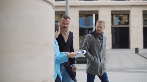 Office Colleagues Talking Outdoors Near Office Building Discussing New Project