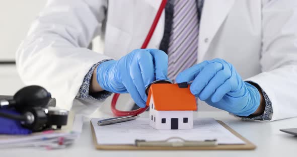 Gloved Doctor Puts Stethoscope Into Toy House  Movie