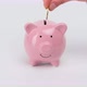 Female hand puts metal coins into the slot of a pink ceramic piggy bank  - VideoHive Item for Sale