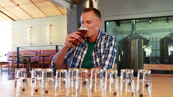 Smiling man having glass of beer at counter 4k