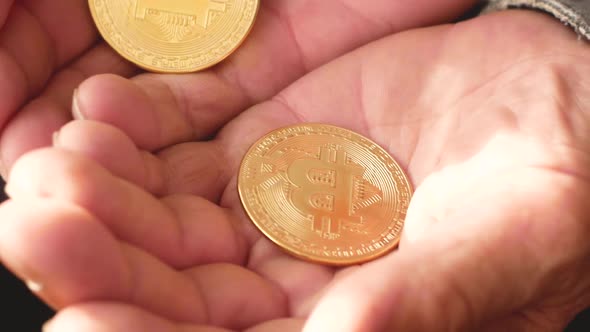 Close-up shot of bitcoin cryptocurrency gold in the hands of an elderly man