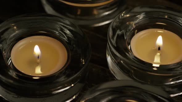 Tea Candles with Flaming Wicks on A Wooden Background